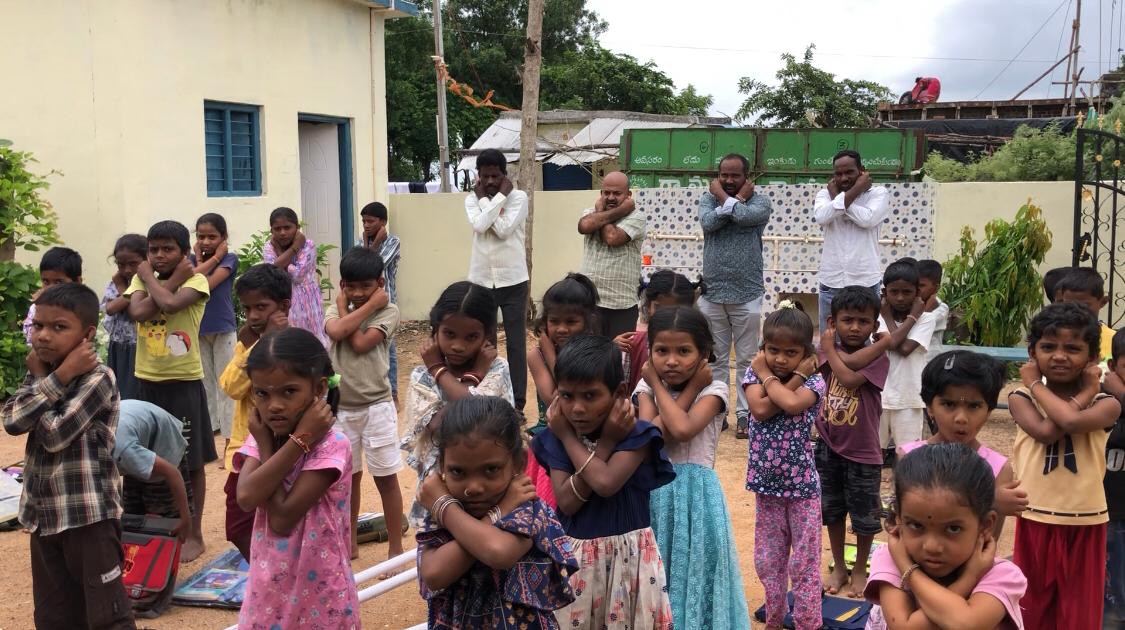 Sarpanch, Staff and students performing 14 rounds of  Super Brain Yoga as part of workshop at Mandal Parishad Primary School, Dharmaram-M, Nizamabad Rural Mandal, sponsored by International Lions Club of Nizamabad-Netha.